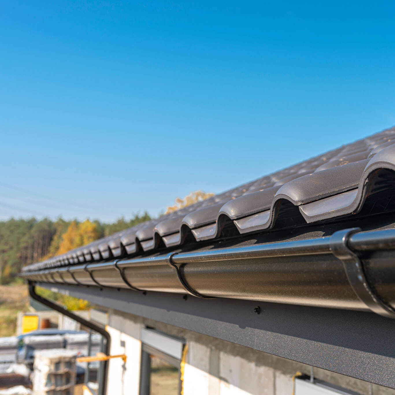a-metal-black-gutter-on-a-roof-covered-with-ceram-2022-11-10-18-00-38-utc-sq